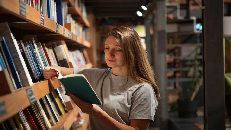 Reader browsing contemporary novels and choosing a book in a bookstore